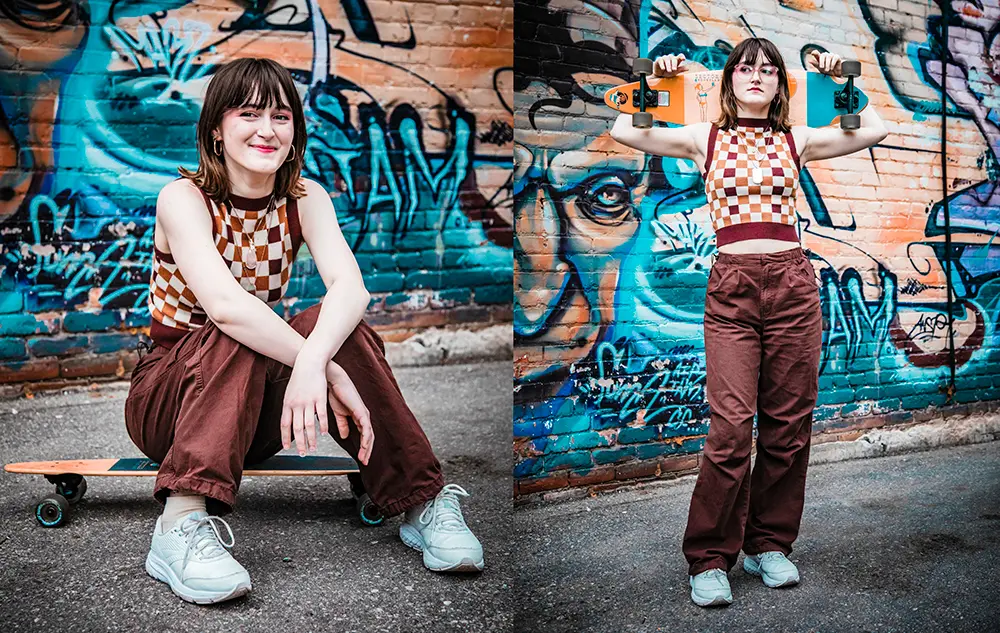 A young woman with brown hair, wearing a checkered top and maroon trousers, poses in two ways in front of a graffiti wall: sitting on a skateboard and standing while holding it up.