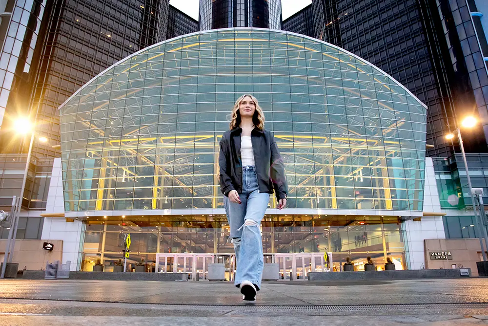 The Best Senior Portraits from Detroit to Ann Arbor - Michigan Photographer A high school senior girl with long hair strides confidently toward the camera, captured by one of the best senior photographers.