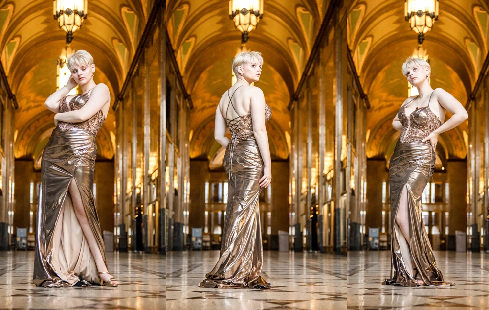 A woman with short blonde hair poses in a metallic gold evening gown with a high slit in downtown Detroit for her Fisher Building senior pictures session with Detroit photographer, Paul Manoian.