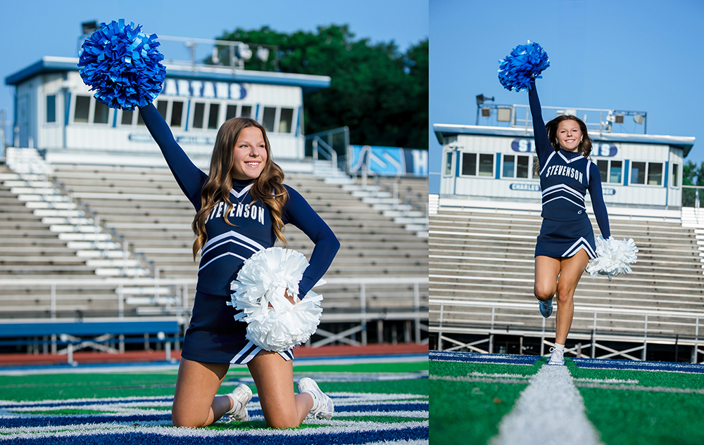 A cheerleader in a navy blue "Stevenson" uniform poses on a football field with blue and white pom-poms, smiling and kneeling with one arm raised in front of empty stadium bleachers.