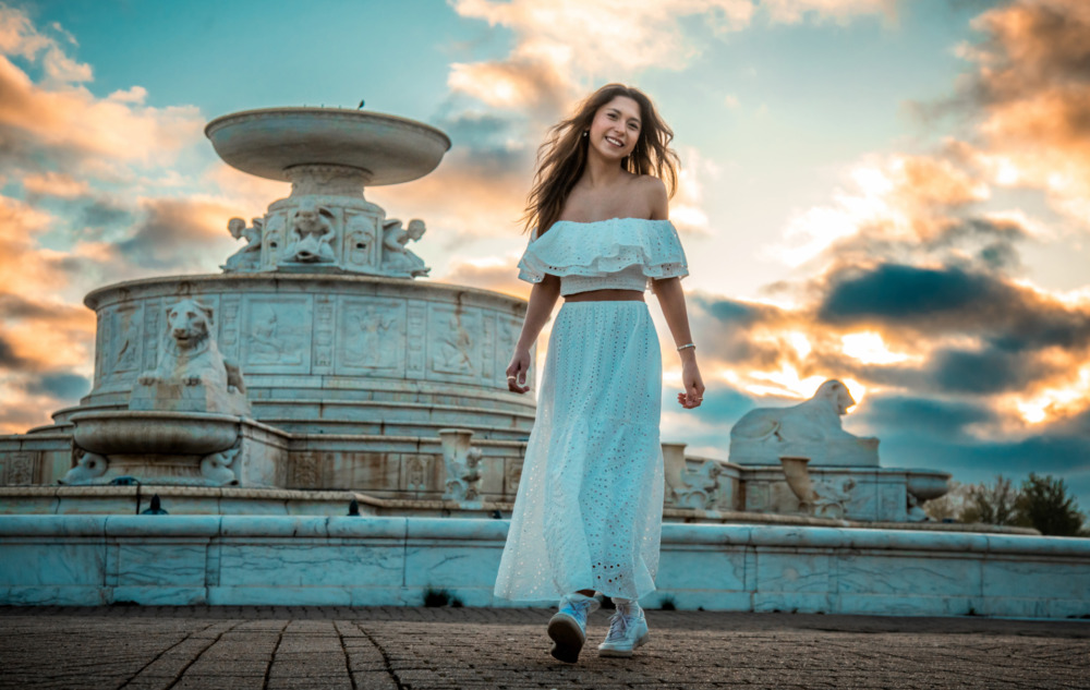 High school senior walking in front of the Belle Isle fountain at sunset during a Detroit senior pictures session
