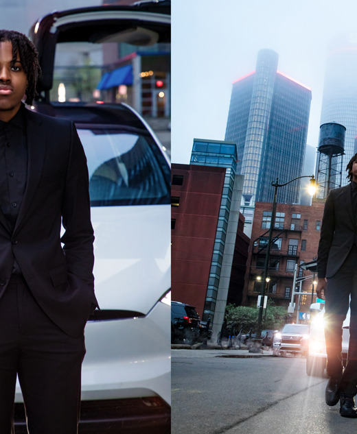 A high school senior in a black suit stands in front of a white Tesla with open doors, capturing the an editorial vibe for his downtown Detroit senior pictures session.