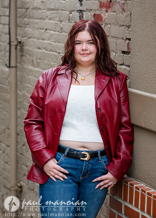 Senior portrait in a red leather jacket against an urban Plymouth backdrop