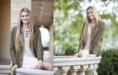 A young woman with long blonde hair, wearing a light dress and olive jacket, sits and smiles in two outdoor settings with greenery and stone railings—capturing the fresh, natural feel of a summer senior pictures session.