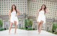 A high school senior in a white dress is posing confidently in front of Michigan Central Station in Detroit, MI for her Detroit senior portraits session with Detroit photographer, Paul Manoian. The dress has an asymmetrical hem, and she is wearing beige heels. She is standing with one hand on her hip in the first image and playing with her hair in the second.