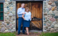 A man and woman stand in front of a door, captured beautifully by a wedding engagement portraits photographer.